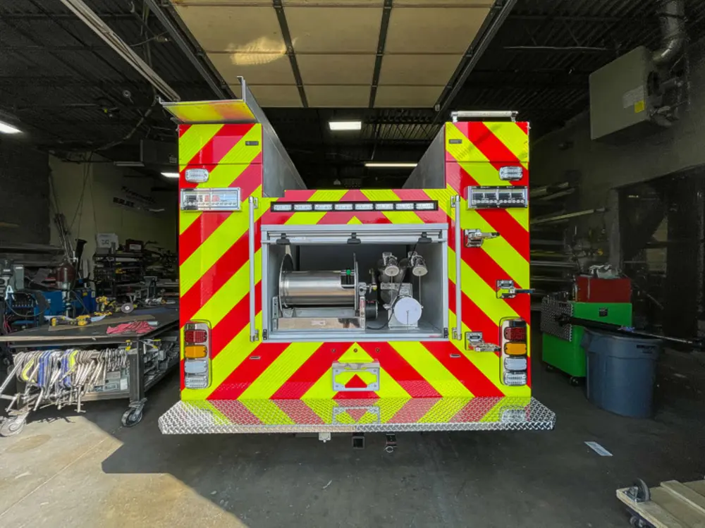 Exterior view of small fire truck showing cab, body compartments, and wheel/tire area.